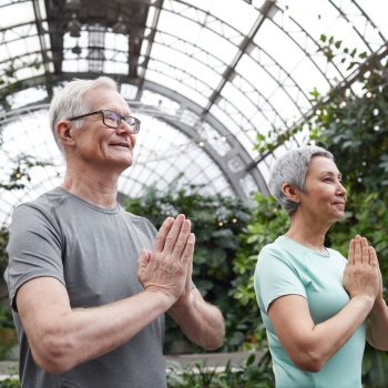 Senior couple enjoying a yoga session indoors, promoting harmony and healthy lifestyle.
